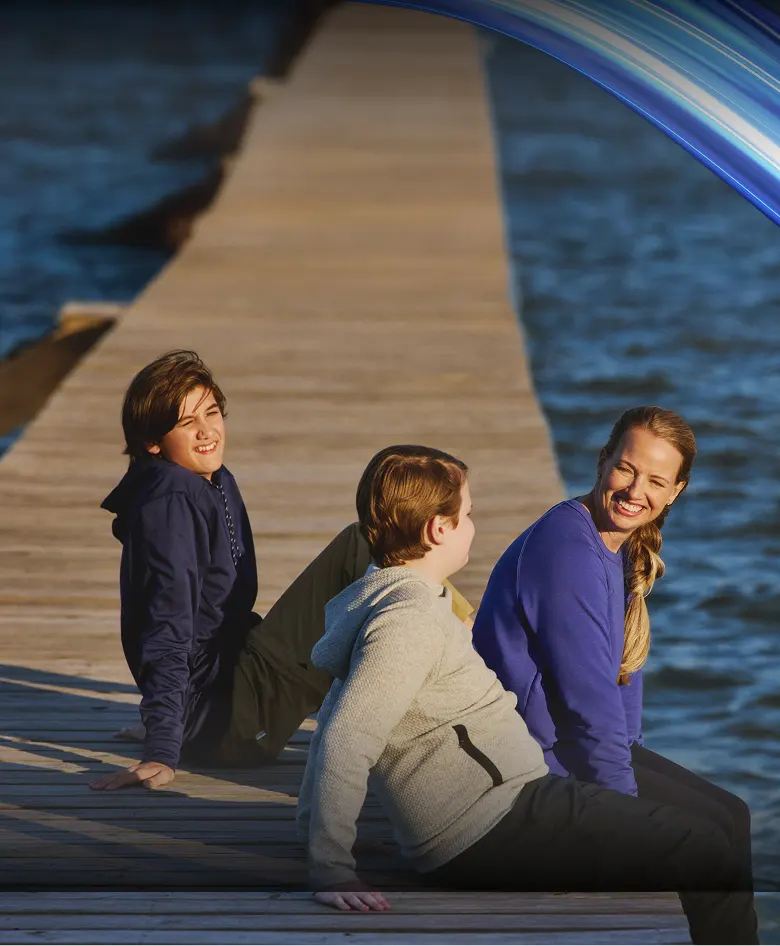 Real EKTERLY® (sebetralstat) patient Cari sitting on a dock with children laughing